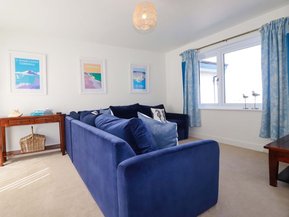 A living room with a blue sofa and a table at Serfaus in Perranporth