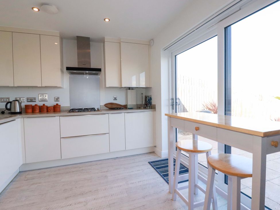 A kitchen with cabinets and a table at Serfaus in Perranporth