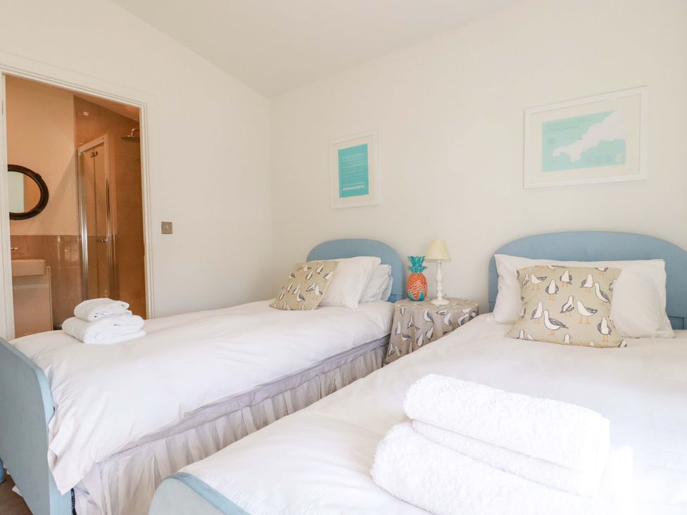 A bedroom with twin beds and a door to the bathroom at Serfaus in Perranporth