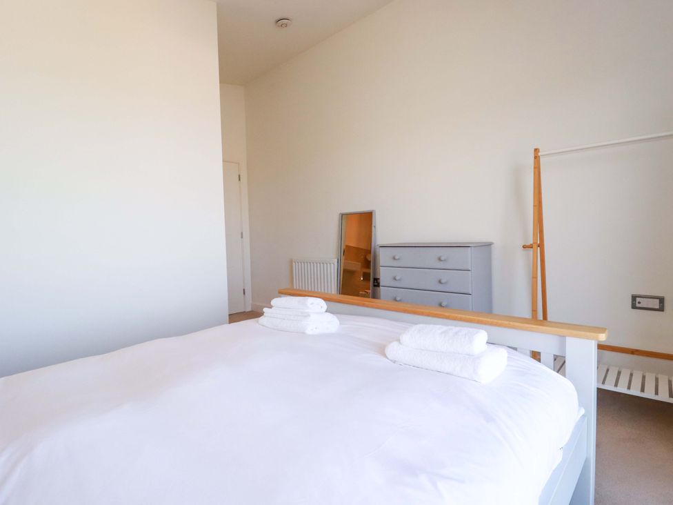 A bedroom with a bed, towels, mirror, and dresser at Serfaus in Perranporth