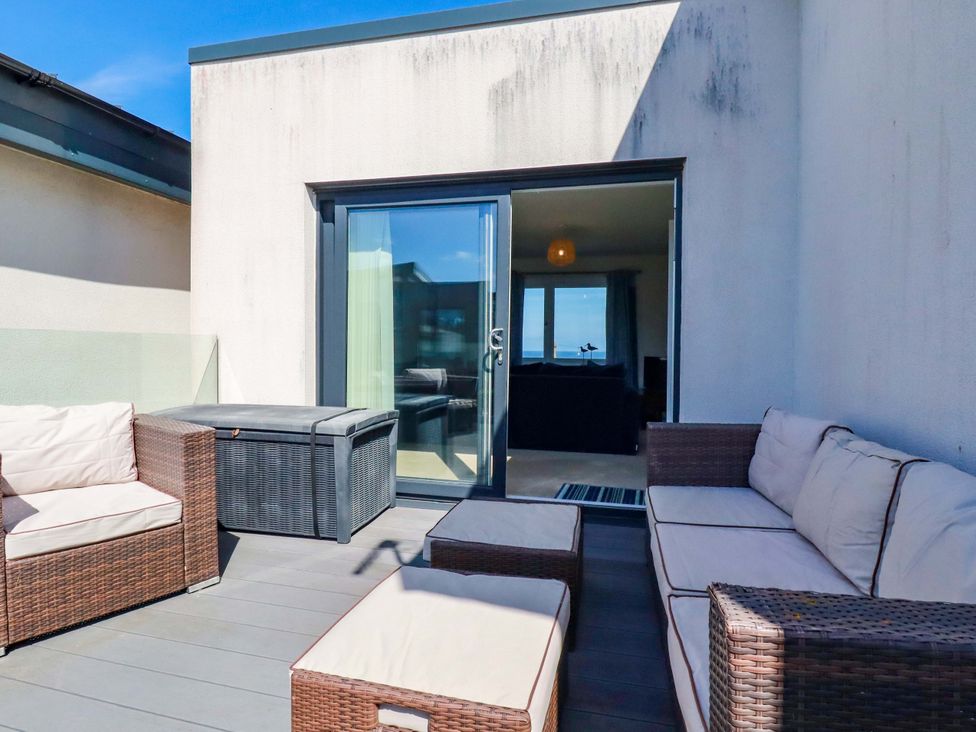 An outdoor terrace with seating and a glass door at Serfaus in Perranporth