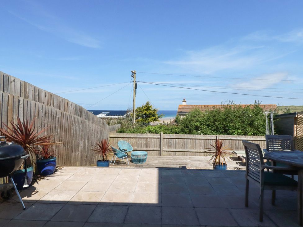 An outdoor patio with a table and chairs overlooking the sea at Serfaus in Perranporth