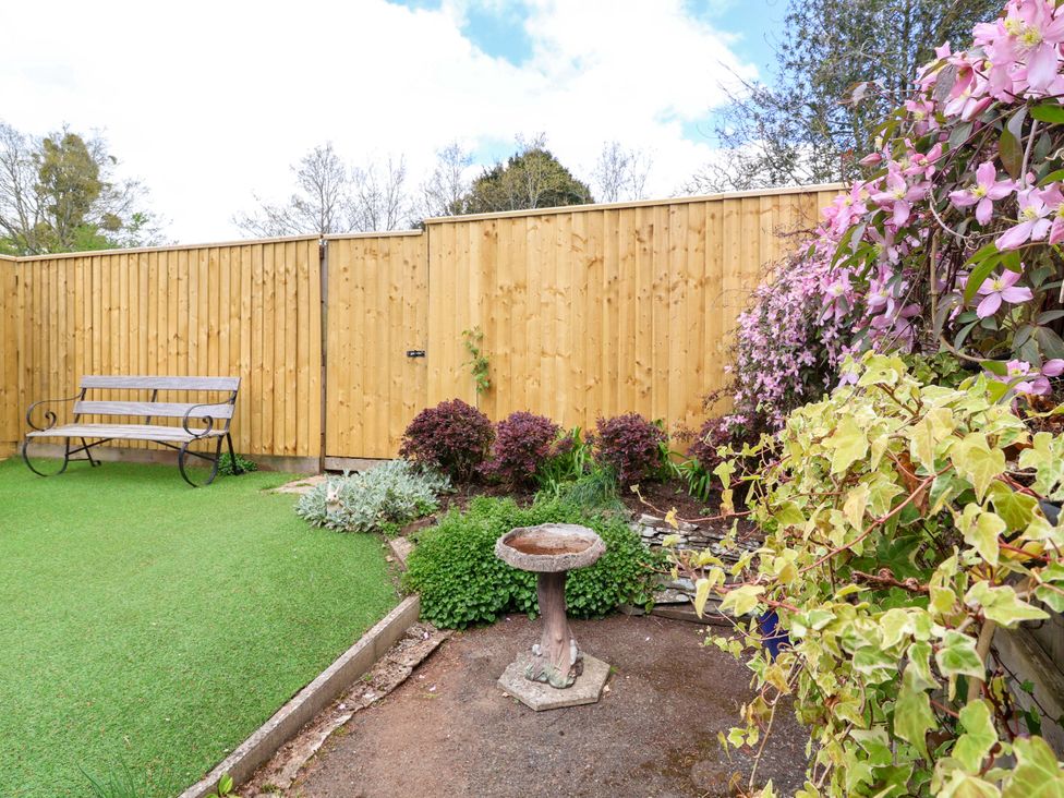 A garden with a bench and flower bed at The Apple Loft in Exeter
