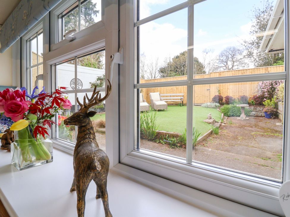 A window view showing a garden with lawn chairs and flowers at The Apple Loft in Exeter