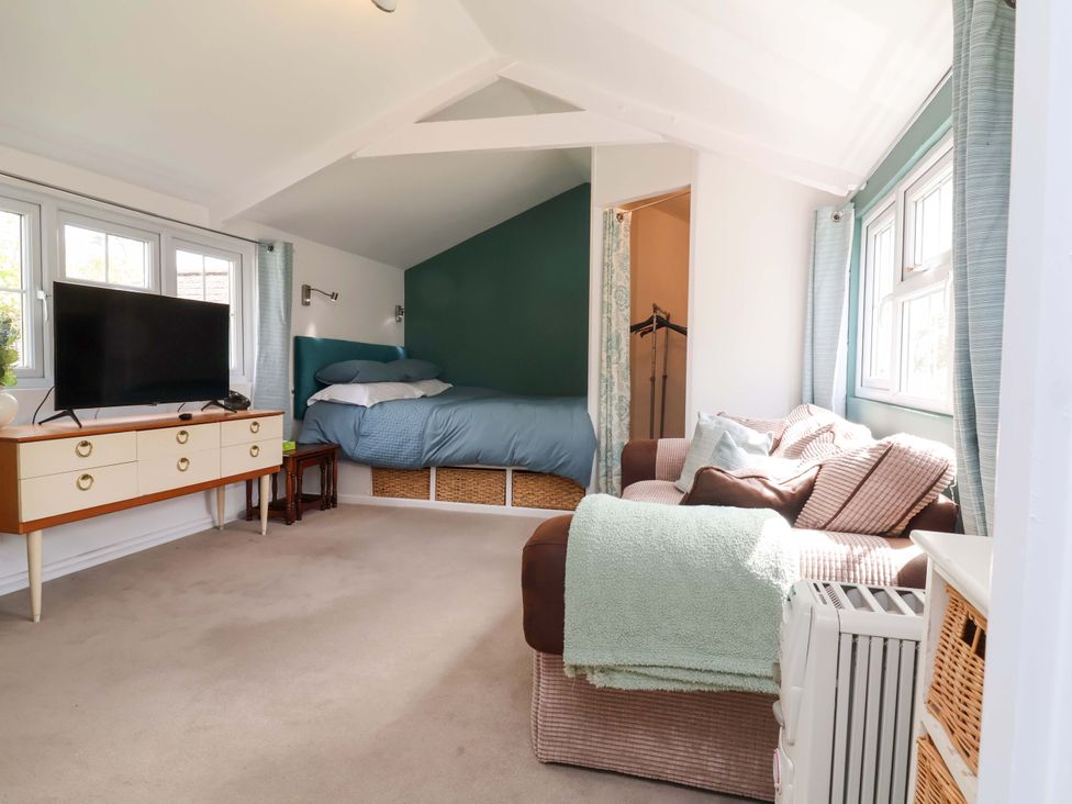 A bedroom with a bed, television, and sofa at The Apple Loft in Exeter