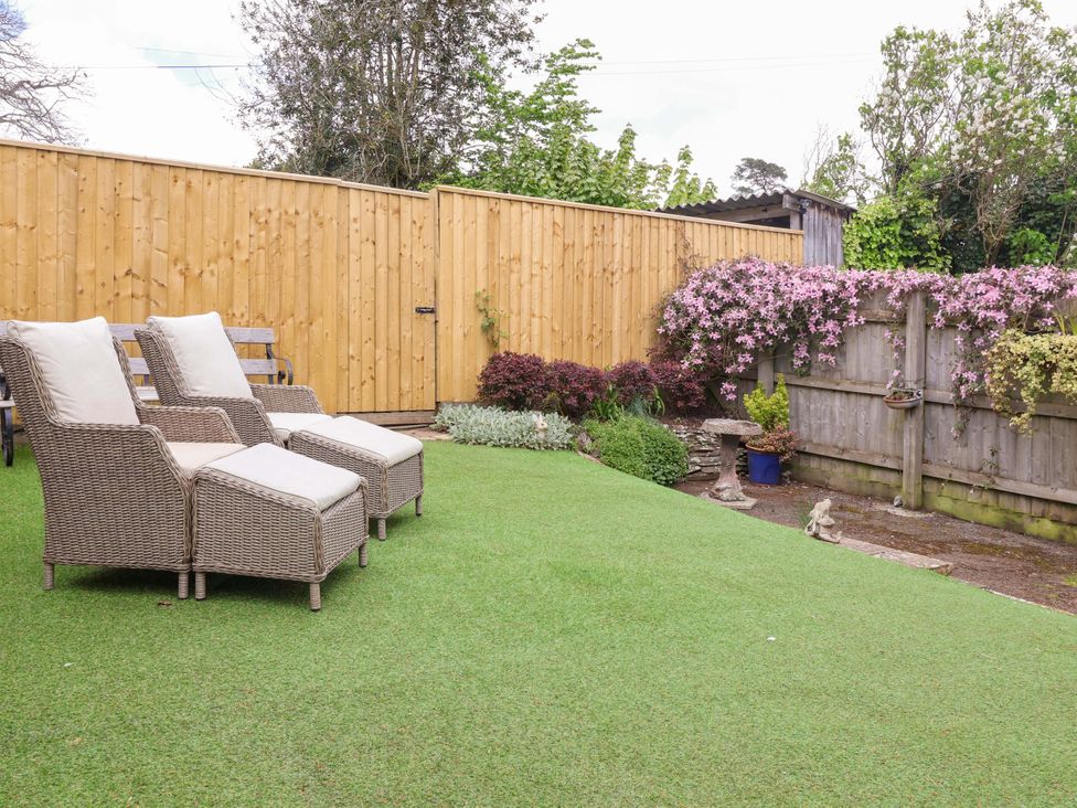 A garden with lounge chairs and flowering plants at The Apple Loft in Exeter