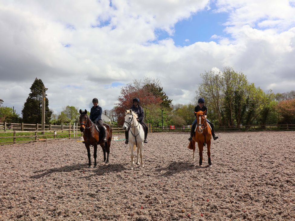 Three riders on horses in a riding arena at The Apple Loft in Exeter
