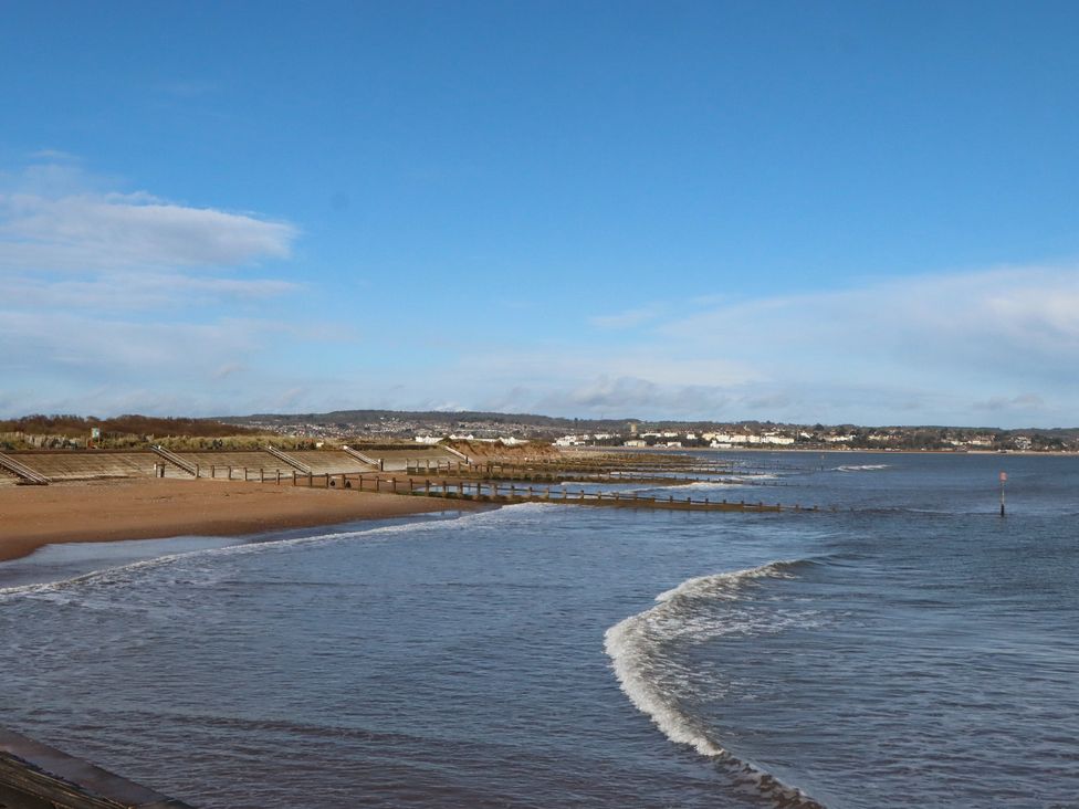 A beach with sand, water, and a pier at The Apple Loft in Exeter