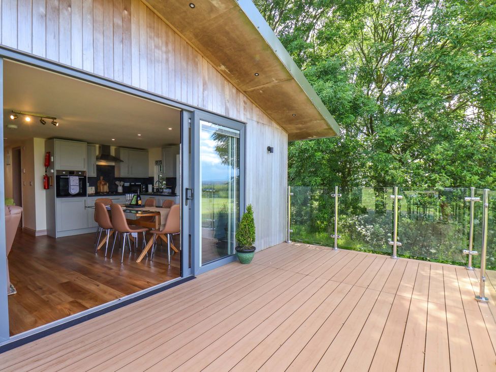 A dining area with a table and chairs visible through sliding doors at Freedom Lodge @ Summerfield Farm Whitby