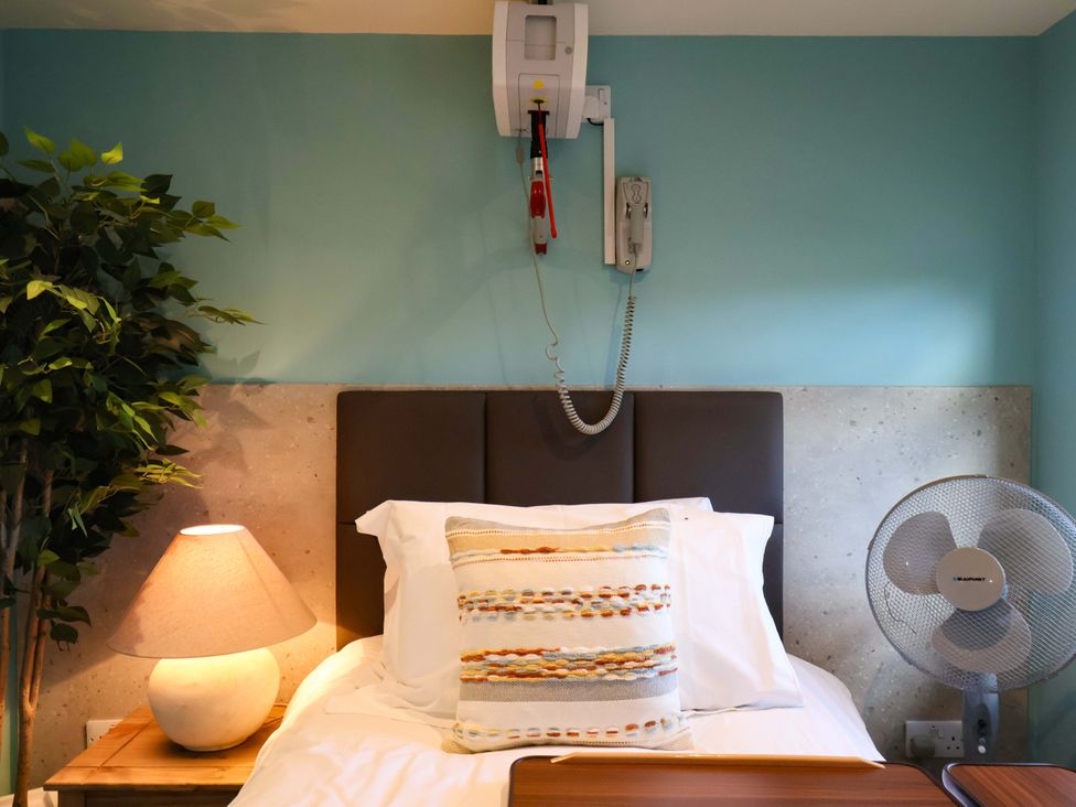A bedroom with a bed, lamp, fan and wall phone at Freedom Lodge @ Summerfield Farm, Whitby