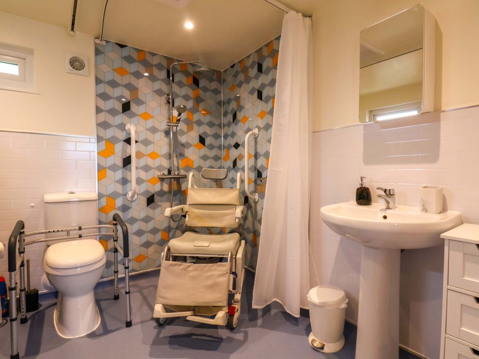 A bathroom with toilet, shower, sink and wheelchair at Freedom Lodge @ Summerfield Farm, Whitby