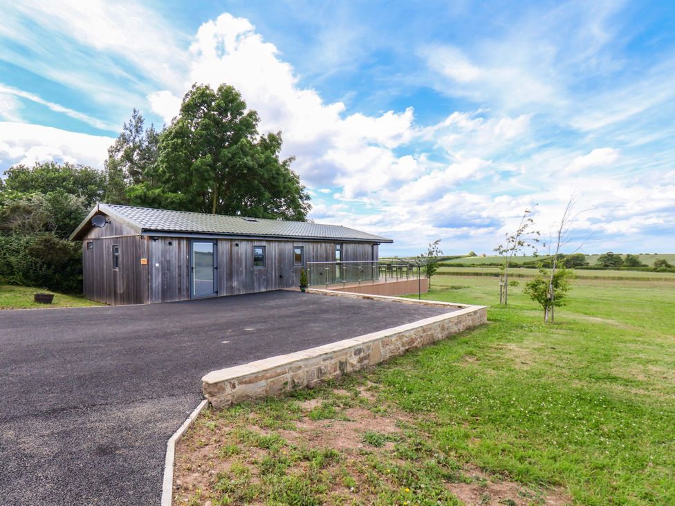 A modern building with a parking area and grass at Freedom Lodge @ Summerfield Farm, Whitby