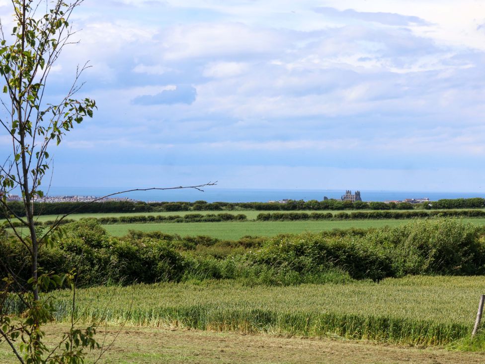 A view of the ocean and fields from a distance at Freedom Lodge @ Summerfield Farm Whitby