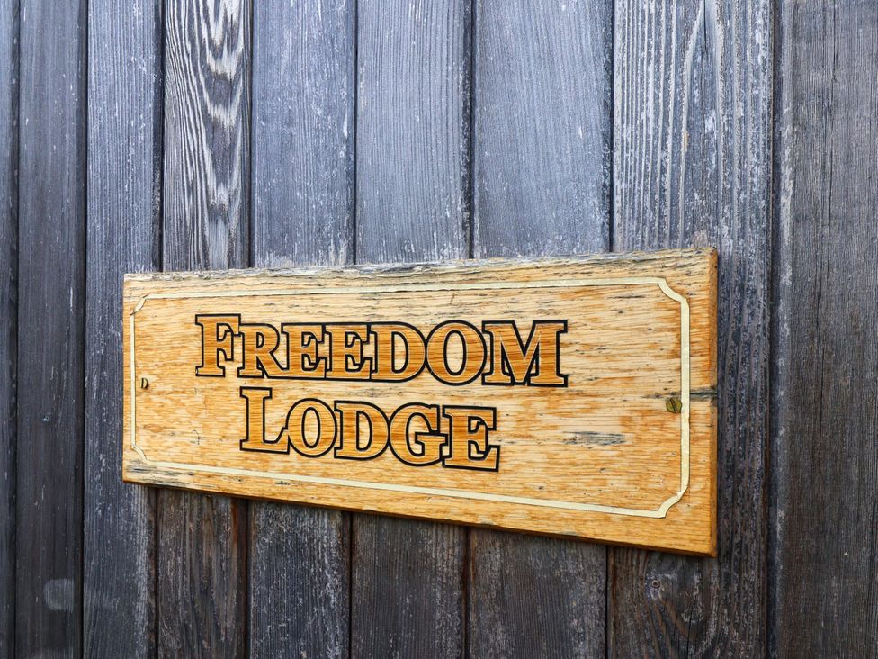 A wooden sign displaying Freedom Lodge at Freedom Lodge @ Summerfield Farm in Whitby