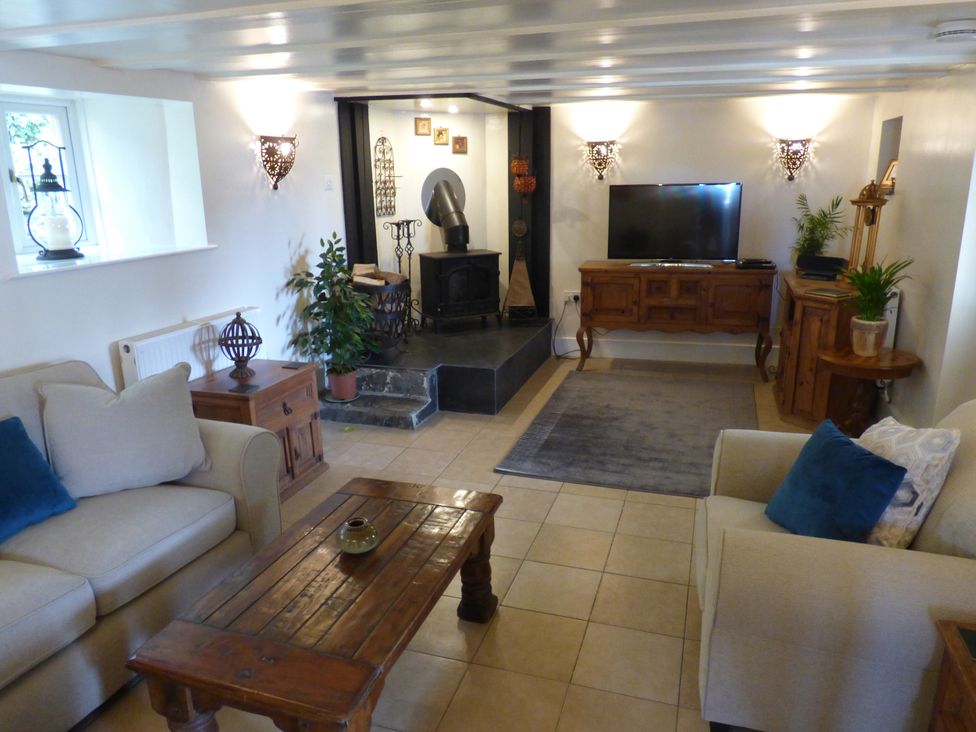 A living room with a television and a fireplace at Trelake Cottage 