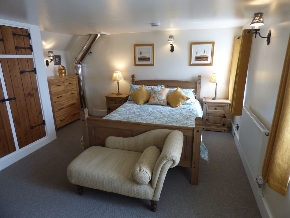 A bedroom with a bed, nightstand, and chest of drawers at Trelake Cottage 
