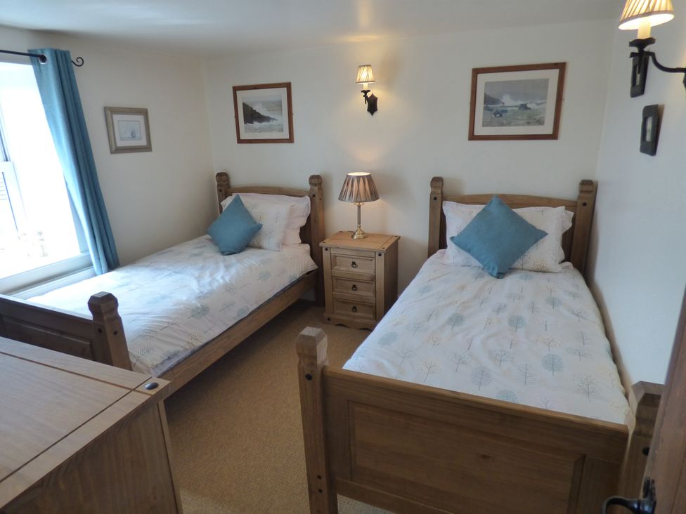 A bedroom with twin beds and a nightstand at Trelake Cottage