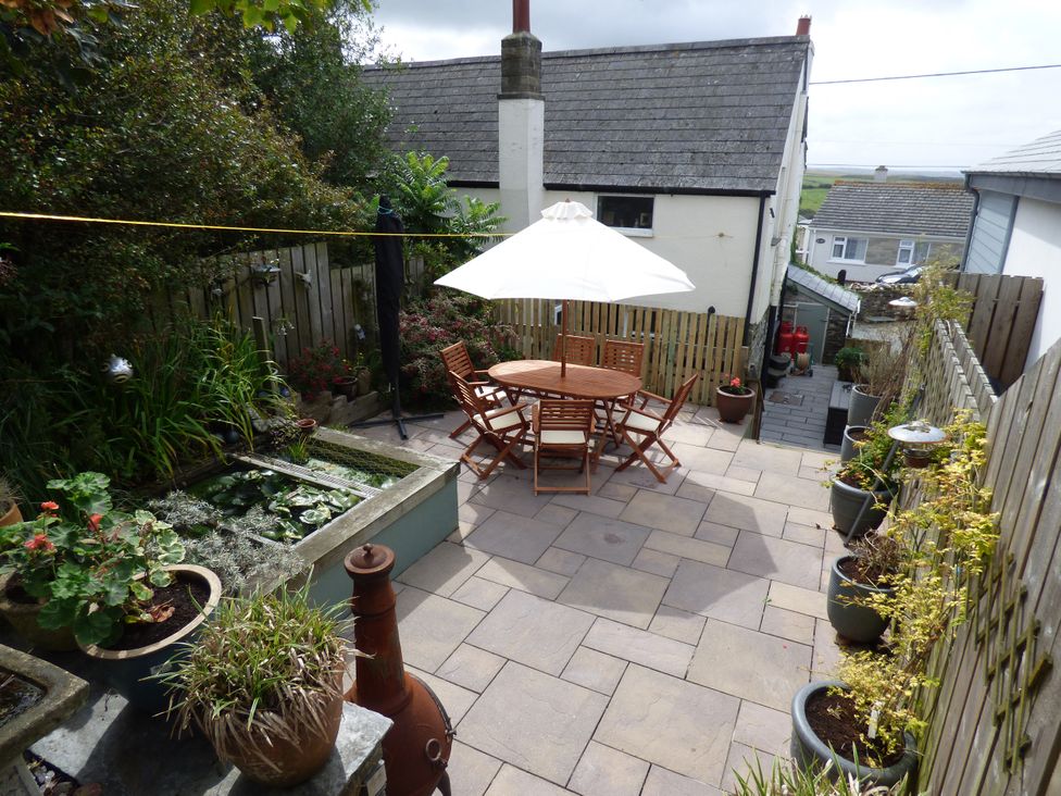 A garden with a table and chairs under an umbrella at Trelake Cottage