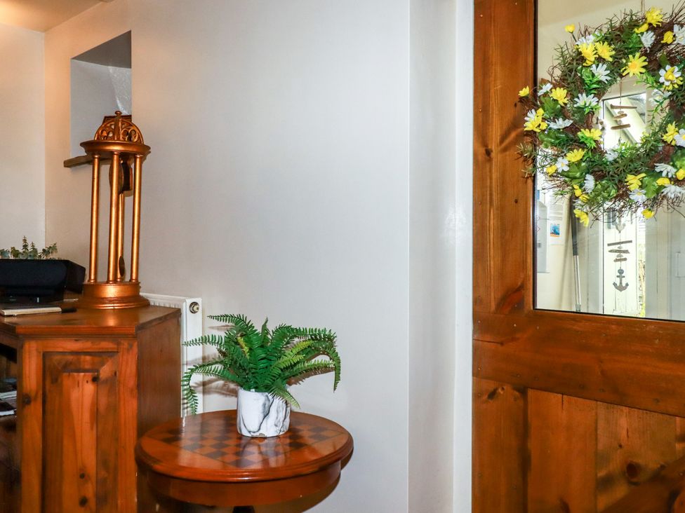 An entryway with a plant and a wooden door with a wreath at Trelake Cottage in Tintagel