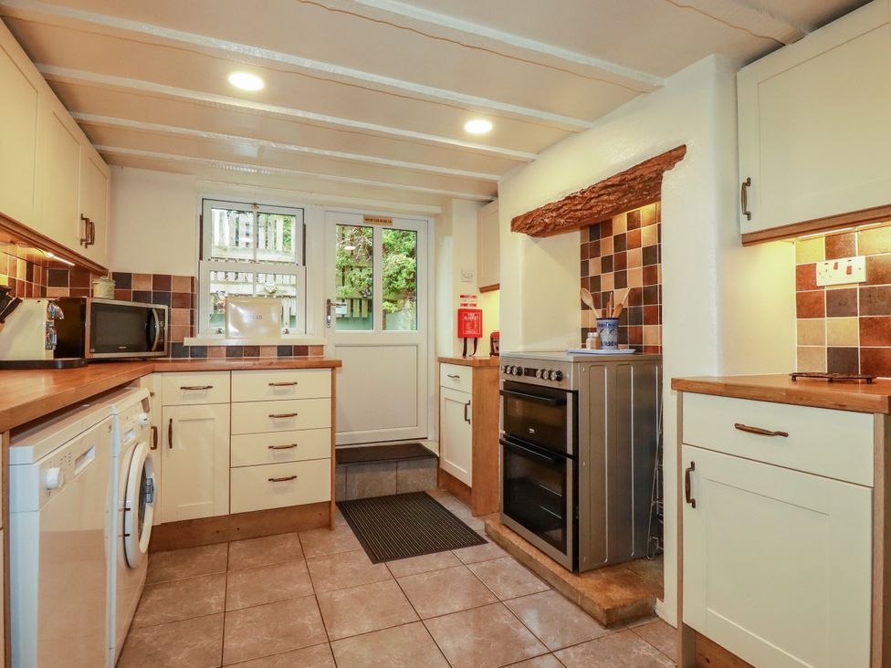 A kitchen with various appliances and a door at Trelake Cottage in Tintagel