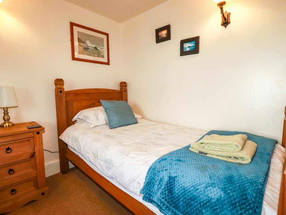 A bedroom with a bed and nightstand at Trelake Cottage in Tintagel