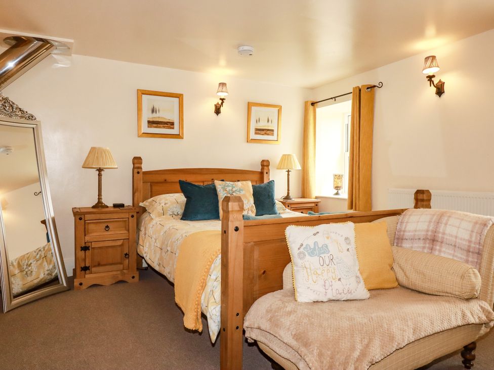 A bedroom with a bed and a mirror at Trelake Cottage in Tintagel
