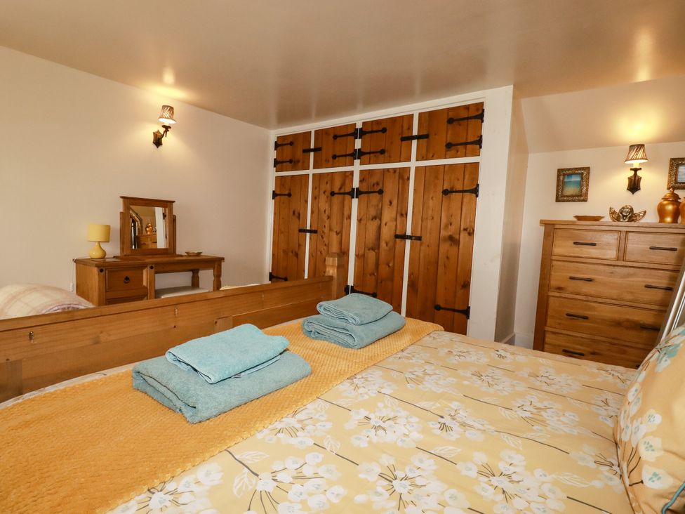 A bedroom with a bed and wooden furniture at Trelake Cottage in Tintagel