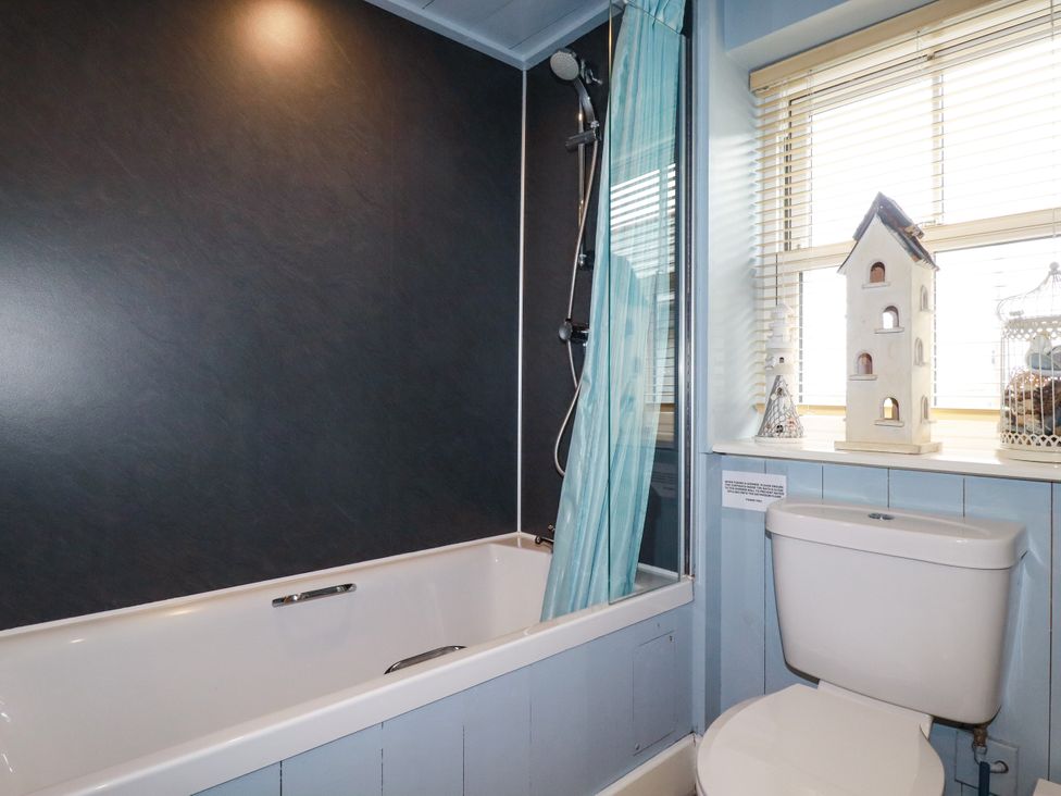 A bathroom with a bathtub, shower, and toilet at Trelake Cottage in Tintagel