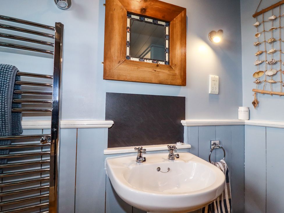 A bathroom with a sink and mirror at Trelake Cottage in Tintagel