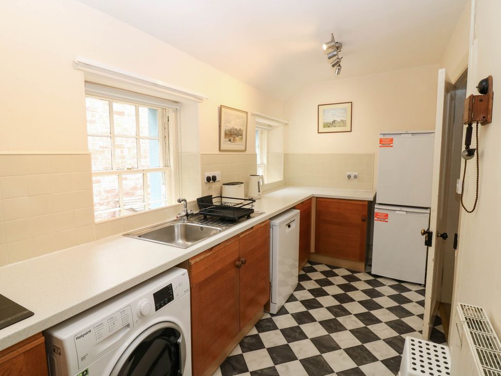 A kitchen with a sink, washing machine, and refrigerator at Gardener’s cottage Stanley