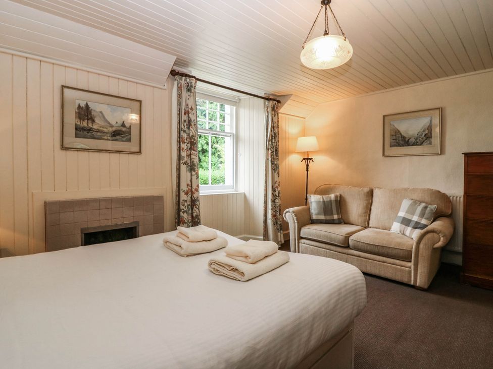 A bedroom with a bed and sofa at Gardener’s cottage in Stanley