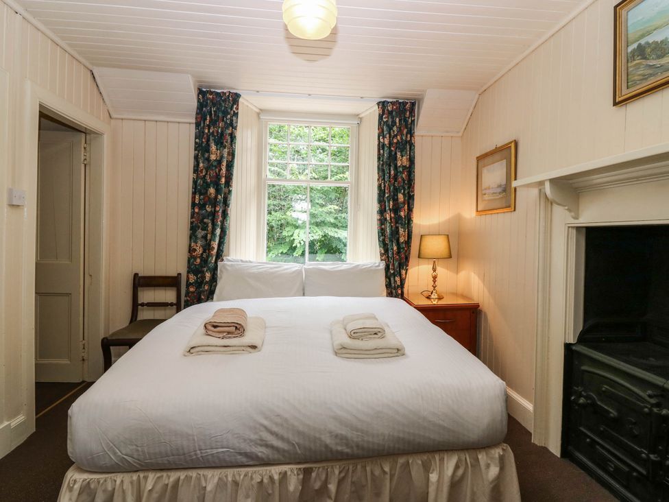 A bedroom with a bed, lamp, and chair at Gardener’s cottage in Stanley
