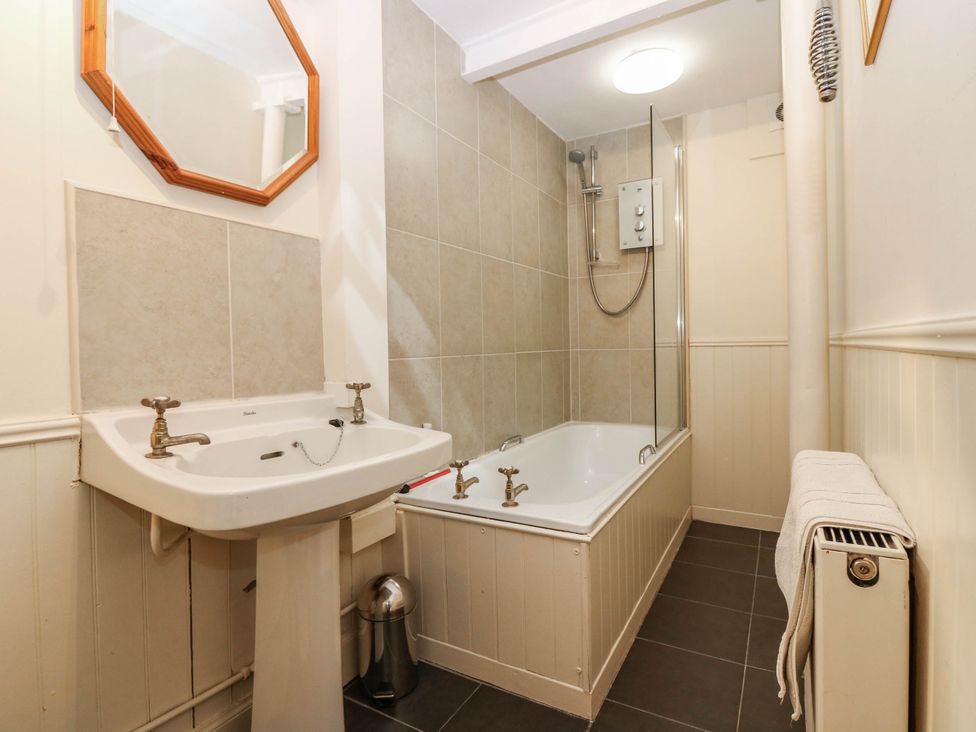 A bathroom with a sink, mirror, shower, bathtub and radiator at Gardener’s cottage in Stanley