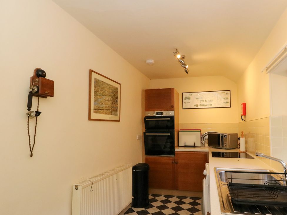 A kitchen featuring a telephone, sink, oven, and microwave at Gardener’s cottage in Stanley