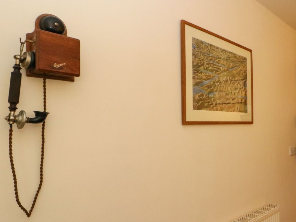 A hallway with a telephone and framed picture at Gardener’s cottage in Stanley