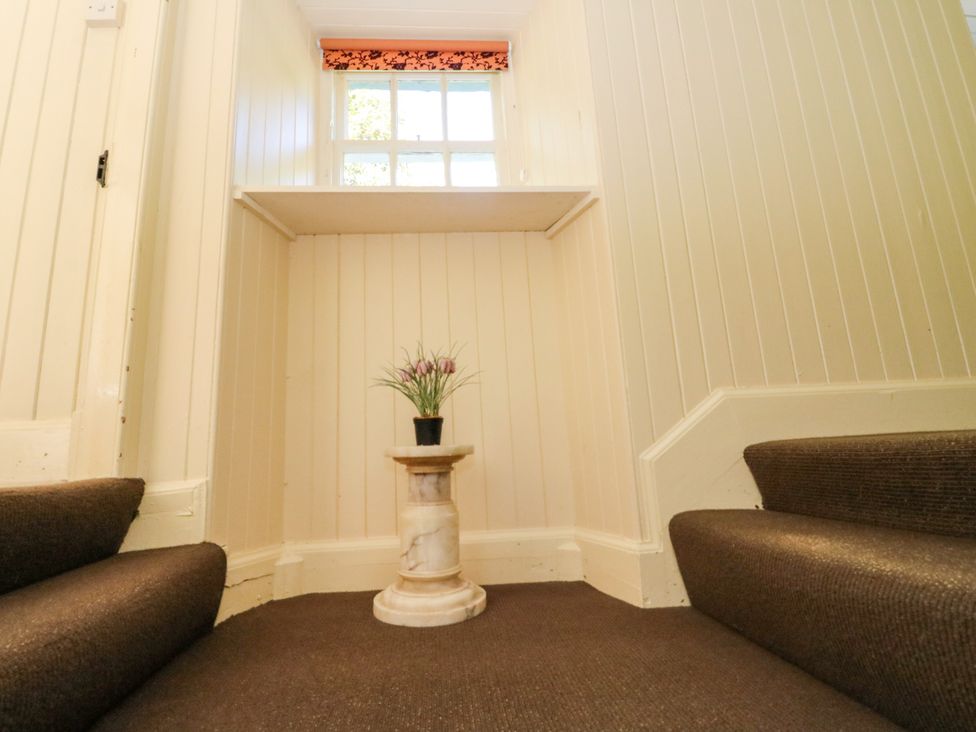A staircase with a table and plant in a hallway at Gardener’s cottage in Stanley