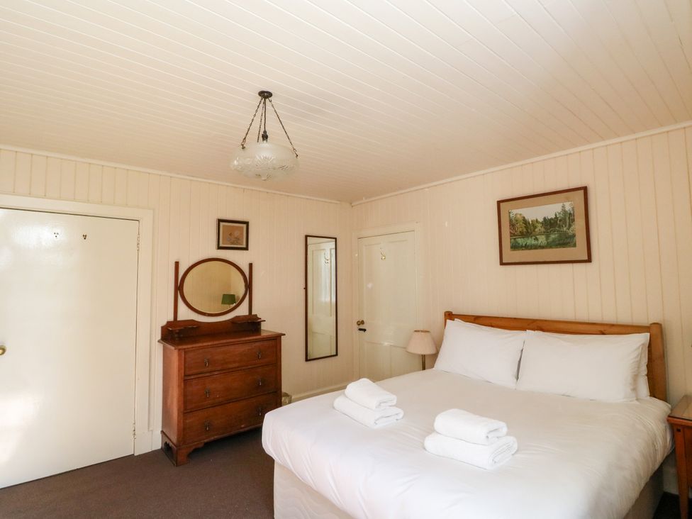 A bedroom with a bed and wooden furniture at Gardener’s cottage in Stanley