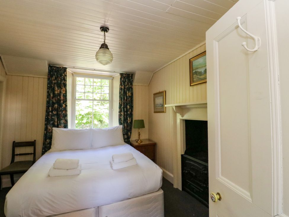 A bedroom with a bed, chair, and window at Gardener’s cottage in Stanley