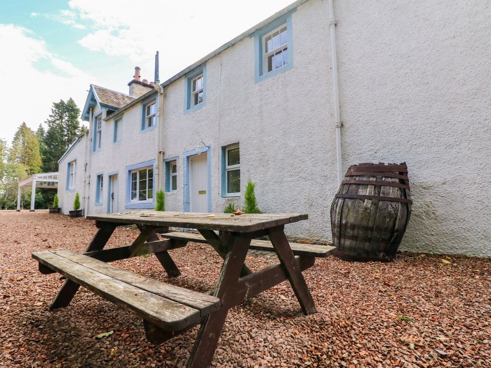 A picnic table with benches outside a building at Gardener’s cottage Stanley