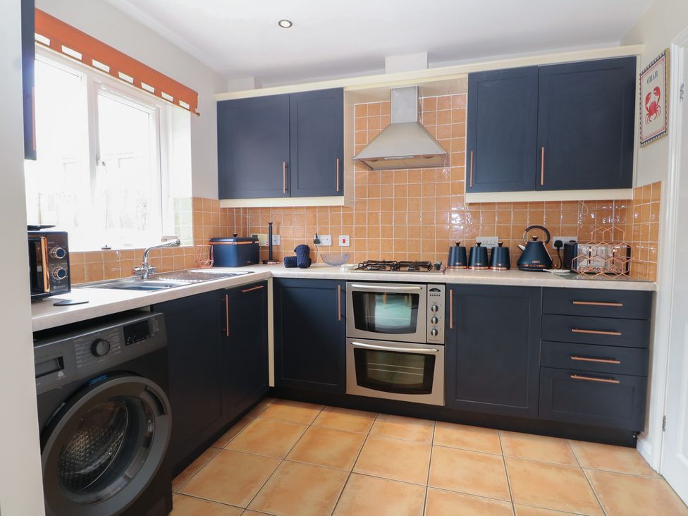 A kitchen with a gas stove and washing machine at The Willows