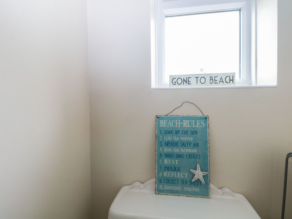 A bathroom with a beach rules sign and a window at The Willows