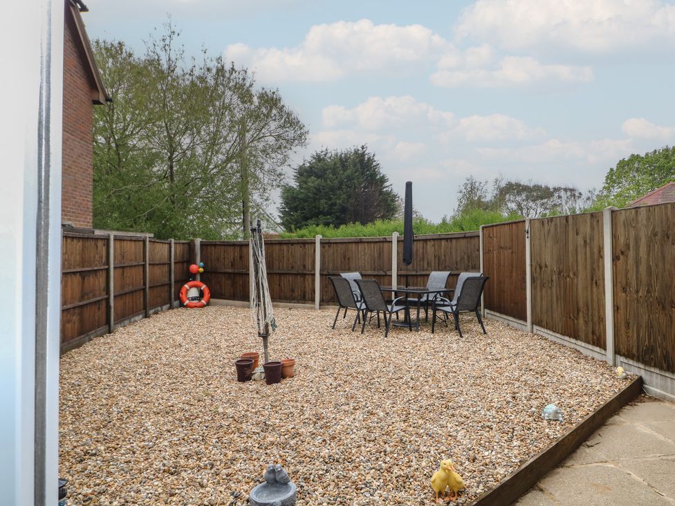 A garden with a table and chairs surrounded by a gravel surface at The Willows 