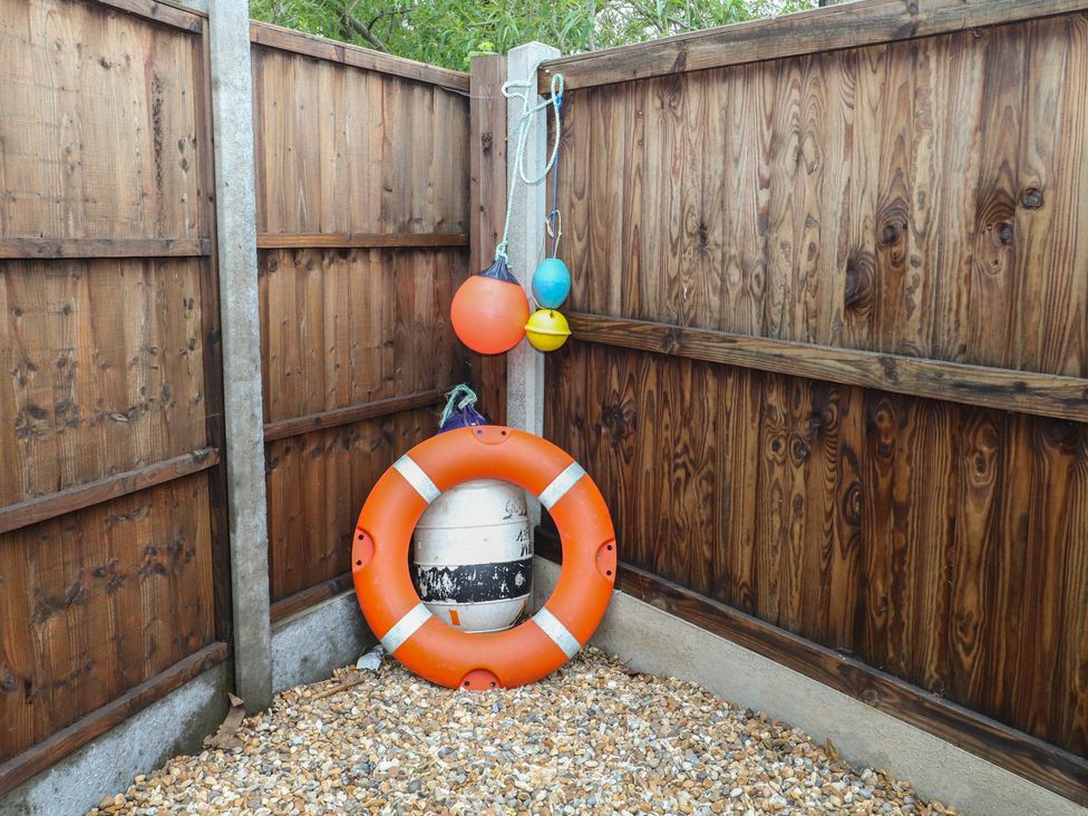 An outdoor area with a life buoy and colored buoys near a wooden fence at The Willows