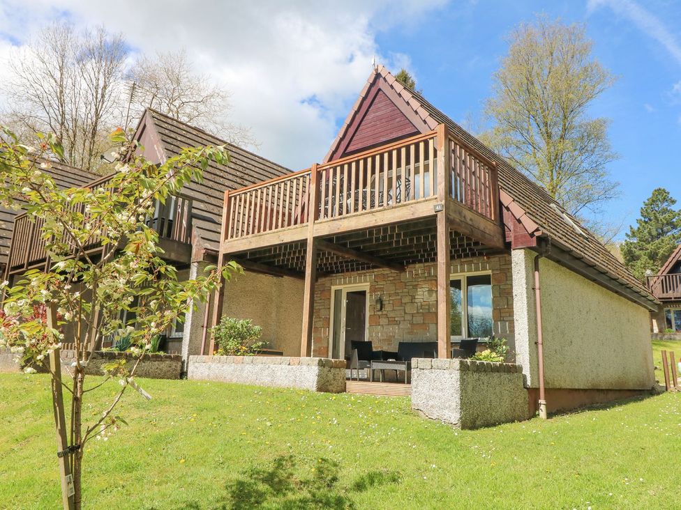 A house with a balcony and grassy area at Honeycombe Lodge