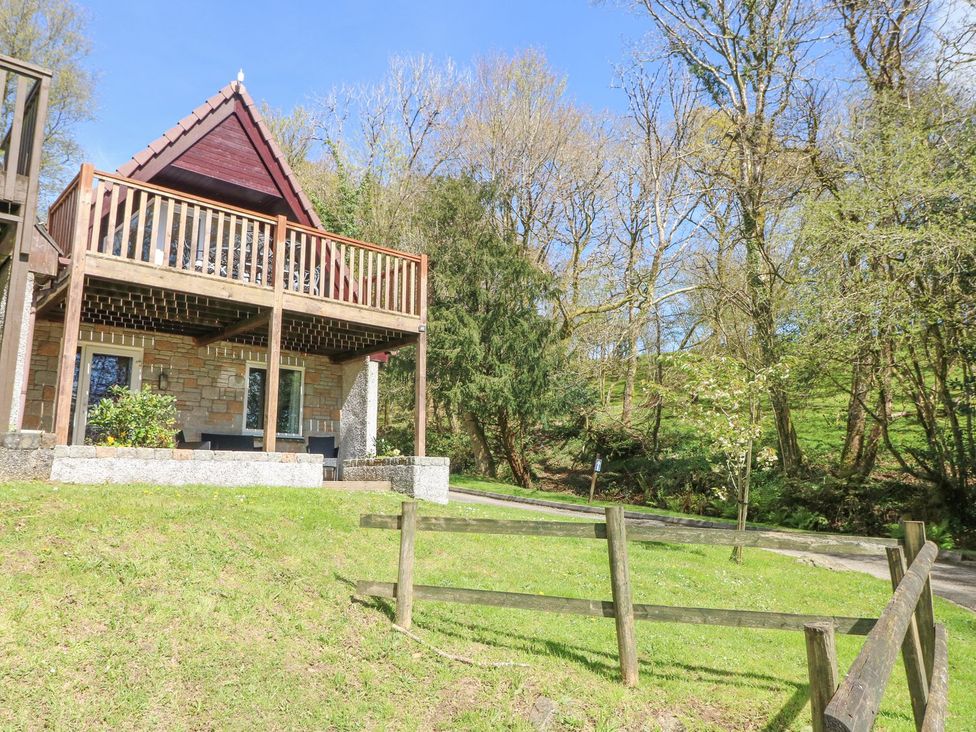 A building with a balcony surrounded by grass and trees at Honeycombe Lodge