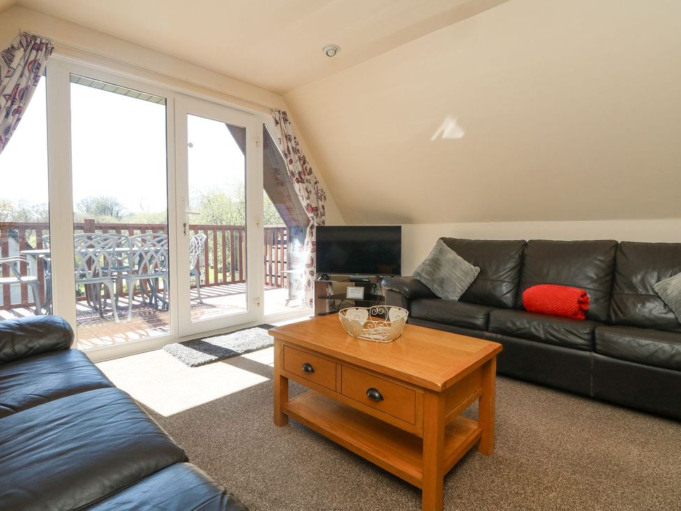 A living room with a coffee table and television at Honeycombe Lodge