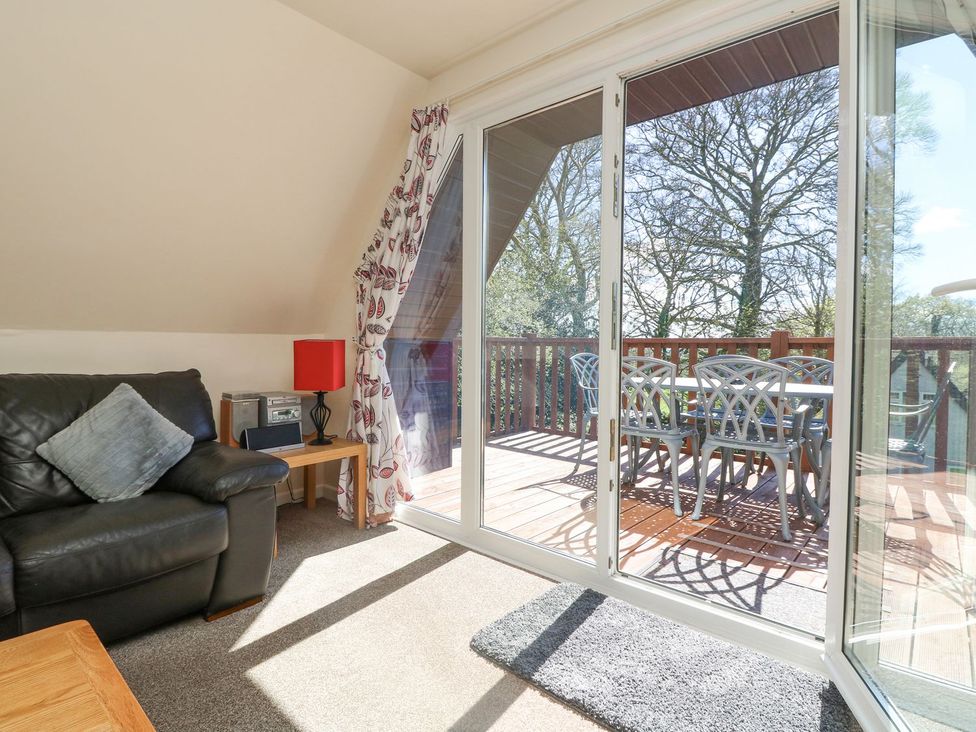 A living room with a sofa and sliding doors leading to a deck at Honeycombe Lodge