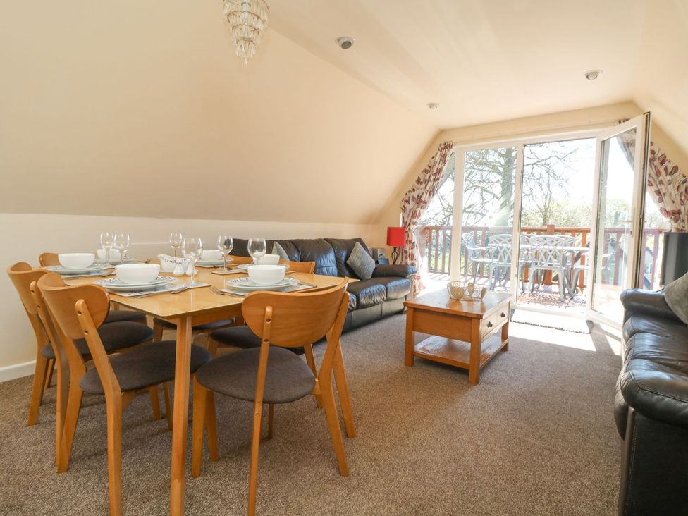 A living room with a dining table and chairs at Honeycombe Lodge