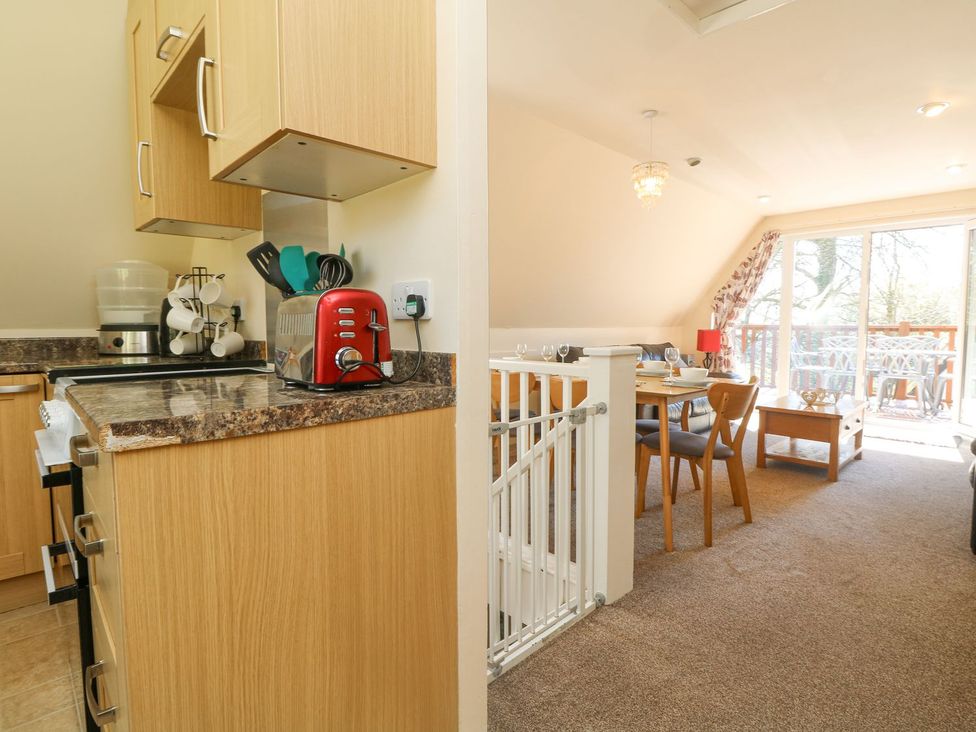 A kitchen with cabinets and a dining area at Honeycombe Lodge