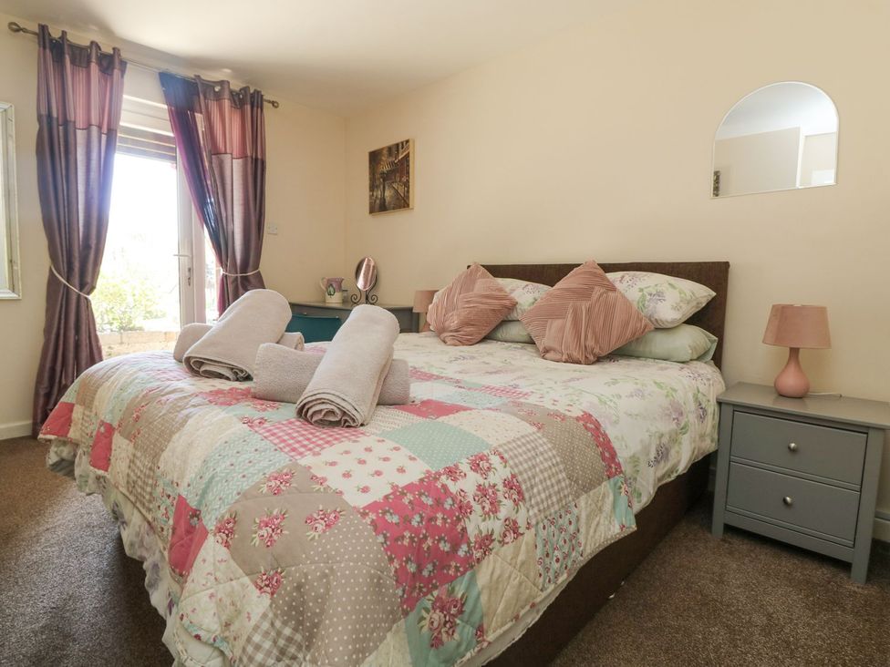 A bedroom with a bed and bedside table at Honeycombe Lodge
